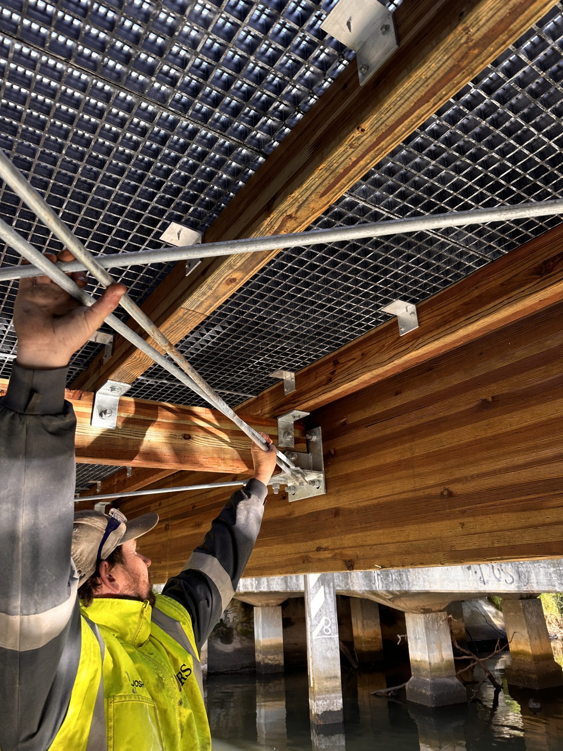 TRS crew member installing finishing detail connectors for Mass timber pedestrian bridge installed in Lorne, VIC, Australia