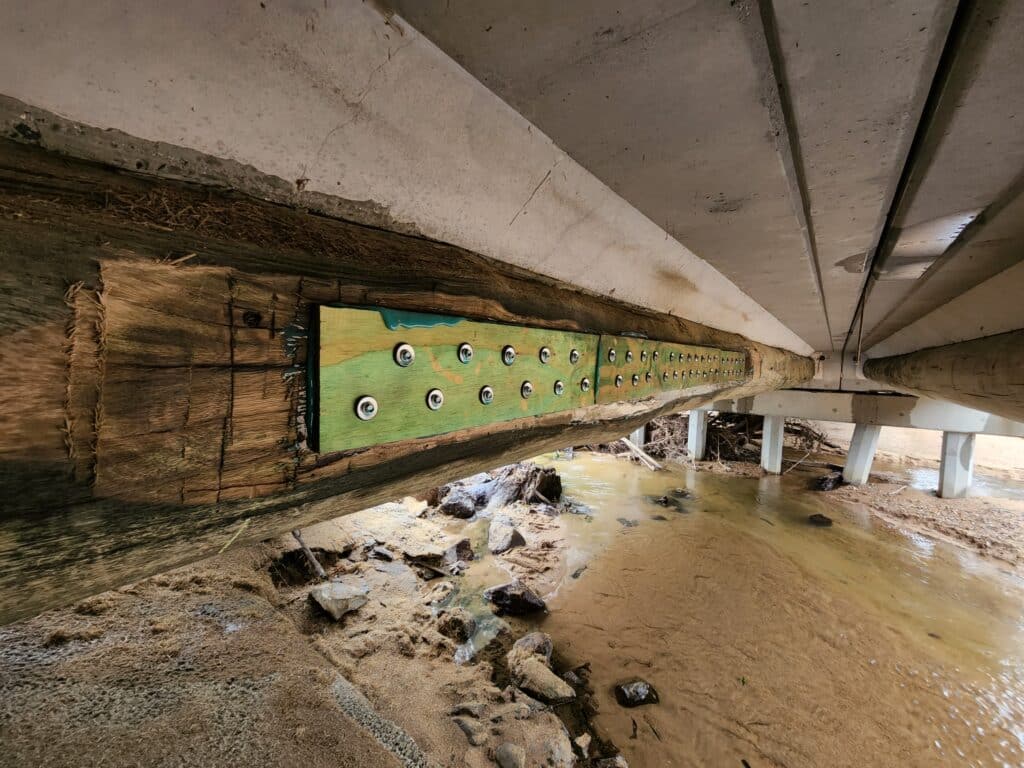 Retroten aramid laminate bonded to the underside of a log girder